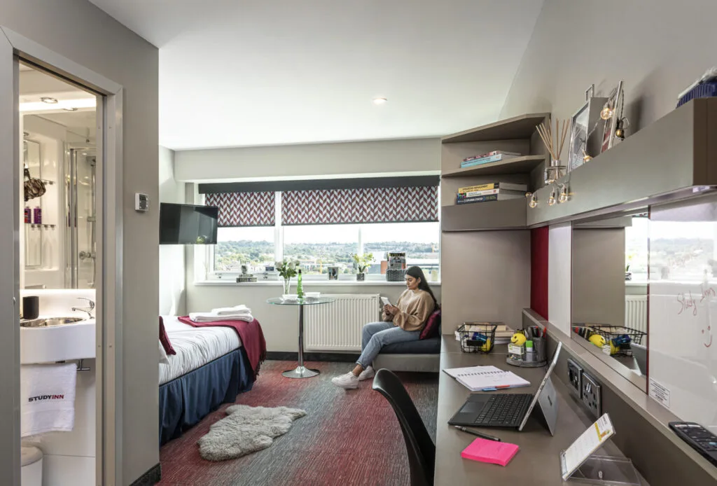 Study Inn bedroom and ensuite bathroom with student reading her tablet by window
