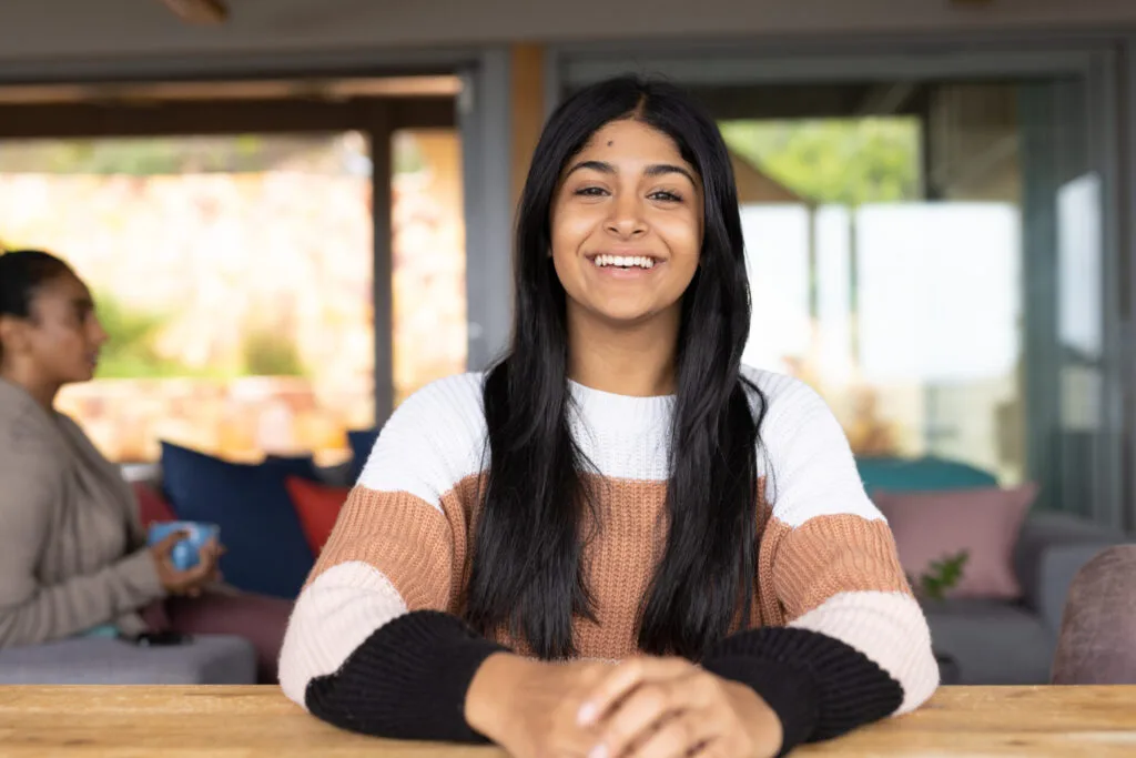 Portrait of happy biracial teenage girl sitting at table