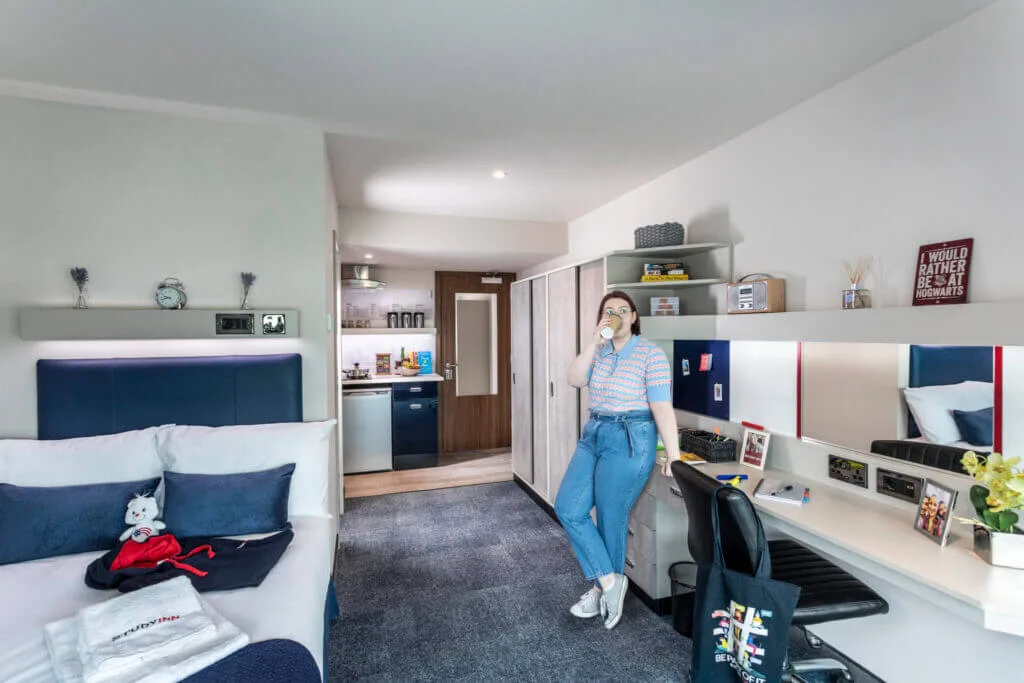 Study Inn Sapphire student studio in Leeds, featuring a student drinking a coffee in her room.
