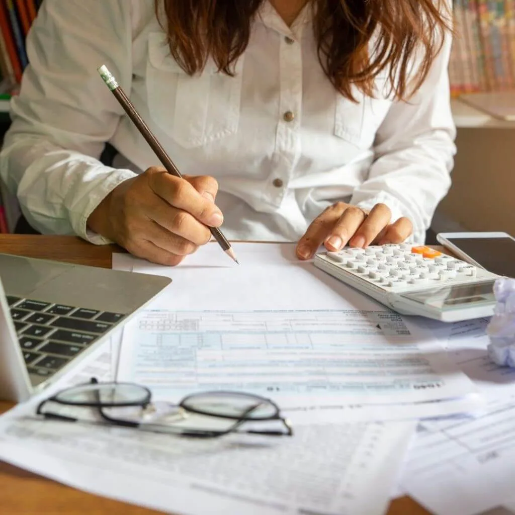A student going through costs of accommodation whilst at university, holding a pencil, and using a calculator amongst bills.