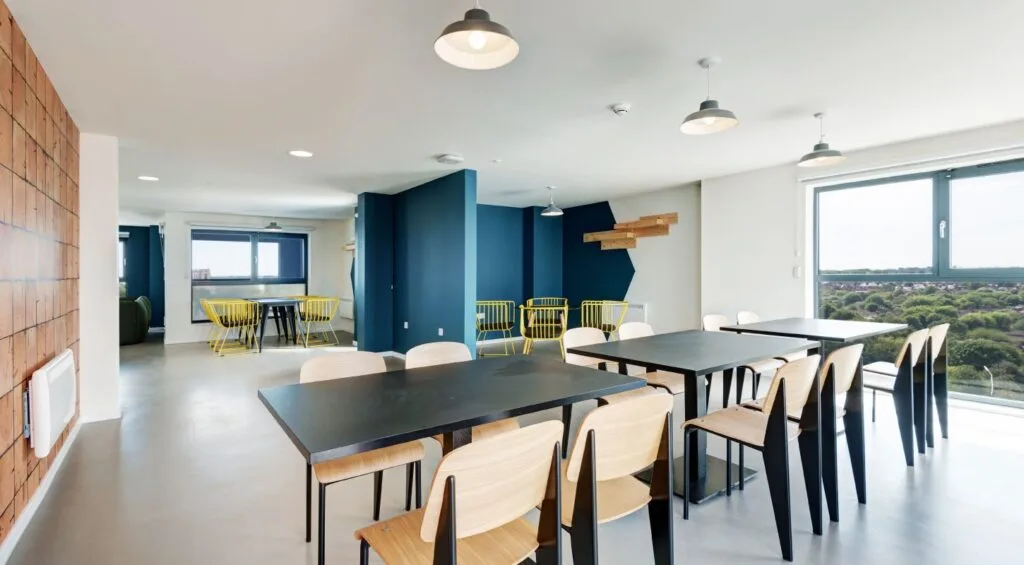 Merlin Height's Sky Lounge, at the top of the student accommodation. View of the city from the windows, and five empty tables with chairs.
