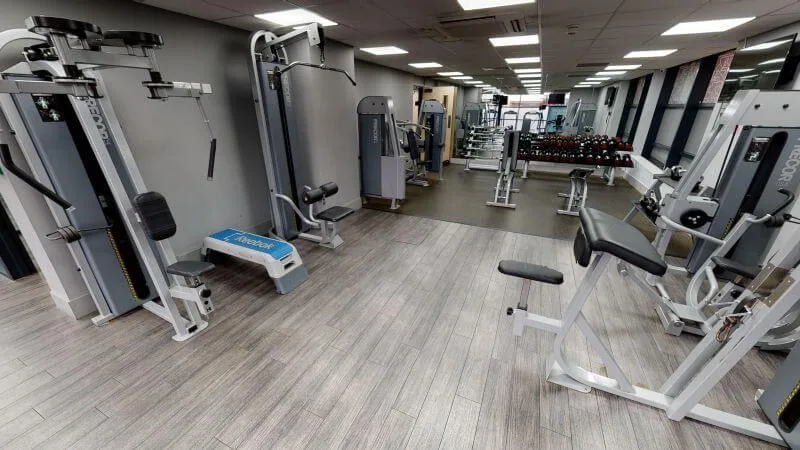 A bright and empty gym with a variety of weights and exercise machines in a student accommodation in Leeds.