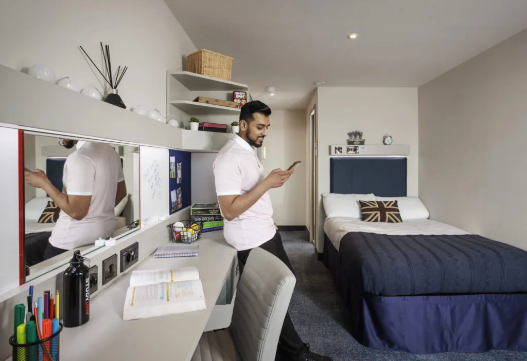 Study Inn Leeds, student accommodation in Leeds. Sapphire apartment with student looking at his phone.