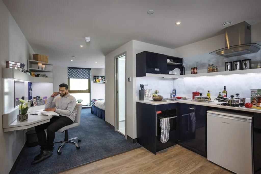 Study Inn Leeds, student accommodation in Leeds. Sapphire Plus studio with student sitting on chair reading a book.