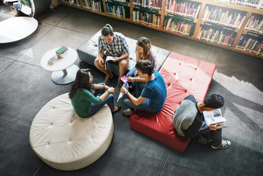 Group of friends relaxing with their laptops in a bright communal area at Exeter student accommodation.
