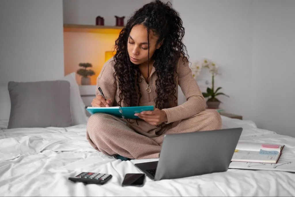 Student sitting on bed managing her finances,  symbolising effective budgeting strategies for affordable student living in Bristol