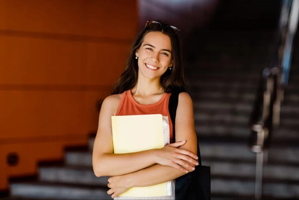 Smiling female student holding folders at luxury student residence in Bristol