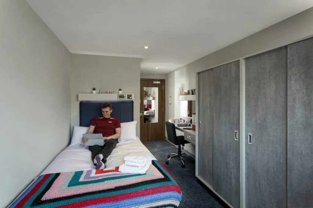 Student relaxing in a modern ensuite room at Study Inn student accommodation in Leicester with private study space.