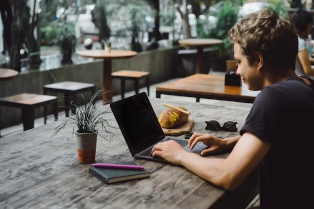 Student studying on a laptop at a cafe table by the window