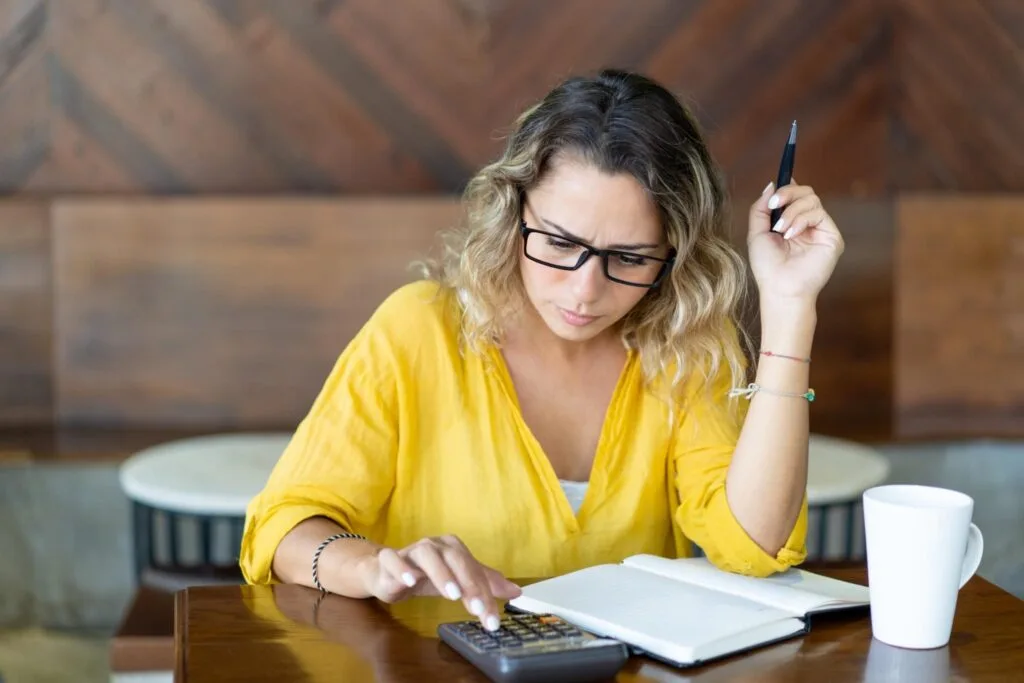 Student working out a monthly budget with a calculator and notebook