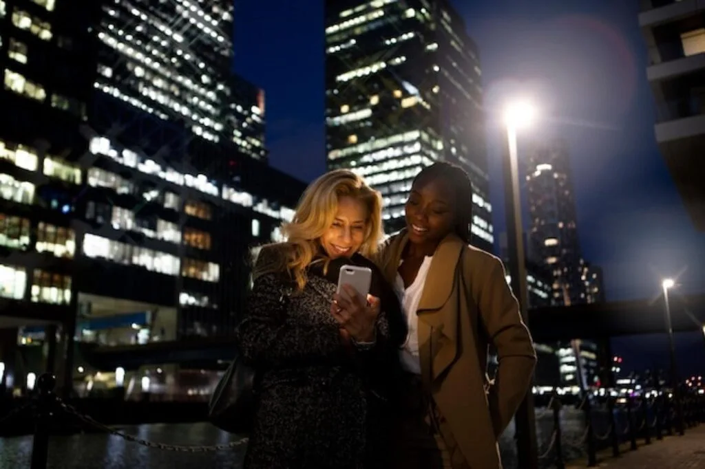 Two students checking a phone on a city street at night