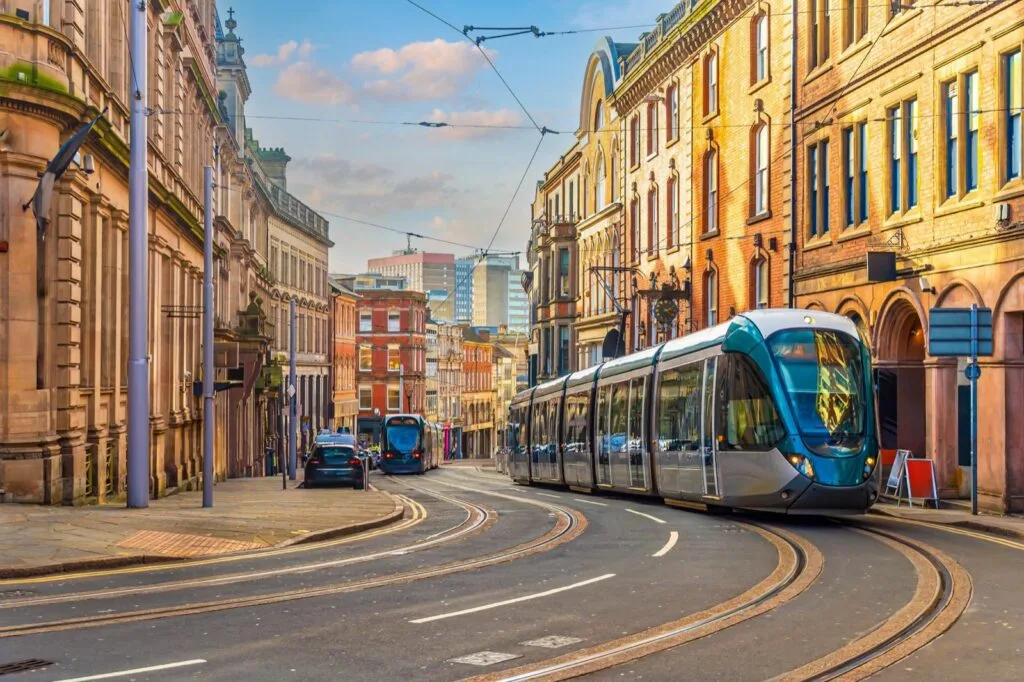A NET tram rounding a bend on a Nottingham city-centre street lined with Victorian buildings